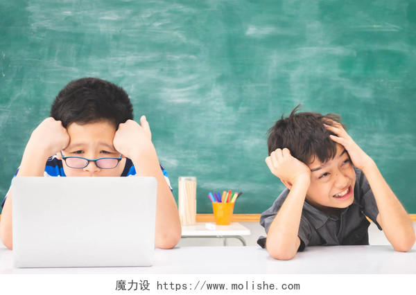 在学校的教室里使用笔记本电脑学习的亚洲学生男孩困扰